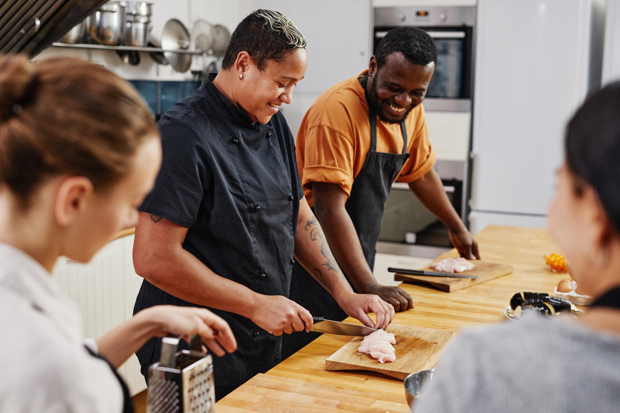 Bright training kitchen with students around a prep table